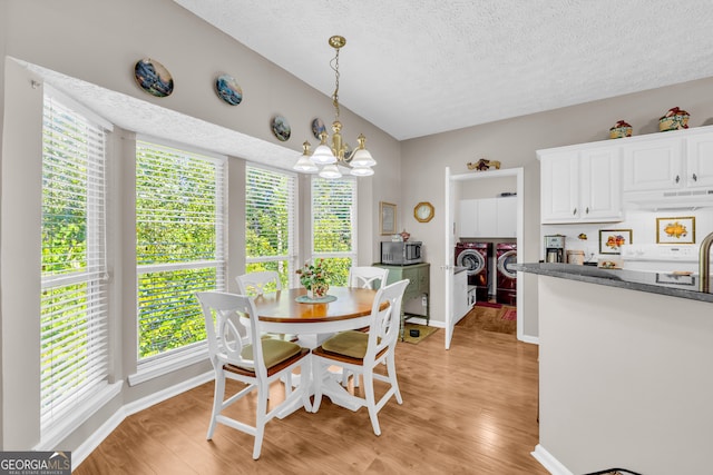 dining space featuring light wood-type flooring, a chandelier, a healthy amount of sunlight, and washing machine and dryer