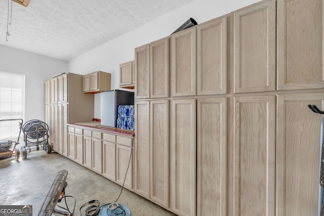 kitchen featuring a textured ceiling, concrete floors, and light brown cabinetry