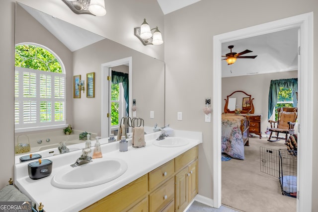 ensuite bathroom with a sink, connected bathroom, ceiling fan, and vaulted ceiling