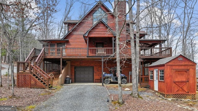 view of front facade featuring a storage unit, gravel driveway, an outdoor structure, an attached garage, and a chimney