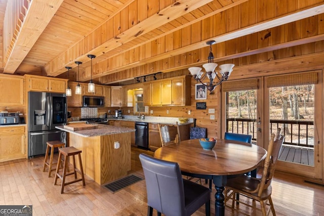 dining space featuring wooden walls, beamed ceiling, wood ceiling, light wood-style floors, and a notable chandelier