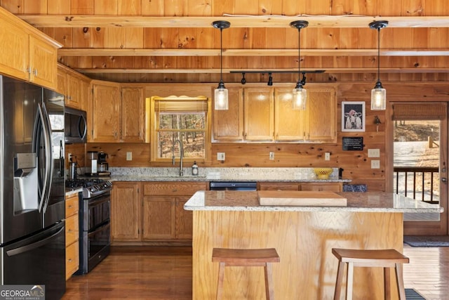 kitchen featuring a breakfast bar, a sink, dark wood-style floors, stainless steel appliances, and light stone countertops