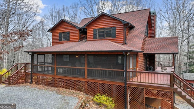 rear view of house with log exterior, stairs, roof with shingles, and a sunroom