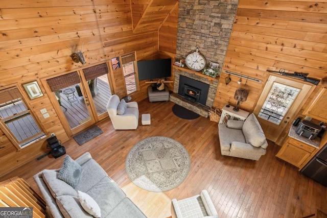 living room featuring hardwood / wood-style floors, wooden walls, and high vaulted ceiling