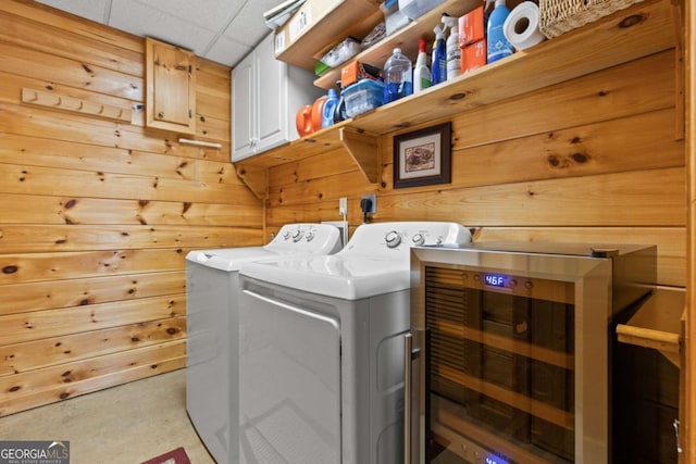 washroom featuring washer and dryer, cabinet space, wooden walls, and beverage cooler