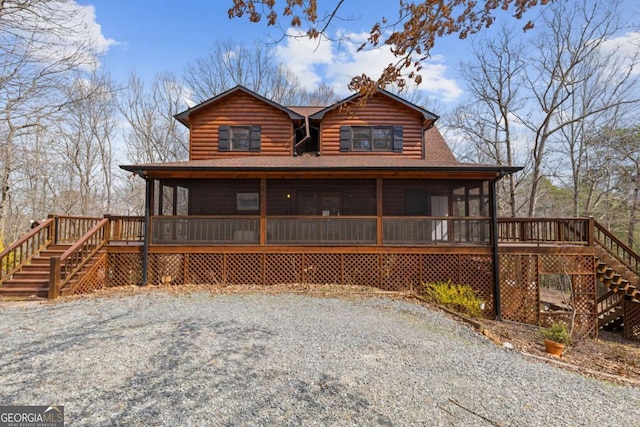 chalet / cabin featuring a shingled roof, stairs, and a sunroom