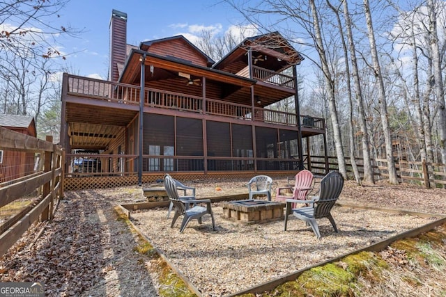 back of property with fence, an outdoor fire pit, a sunroom, a chimney, and faux log siding