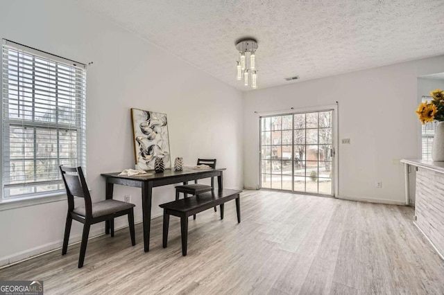 dining area with wood finished floors, a wealth of natural light, and a textured ceiling