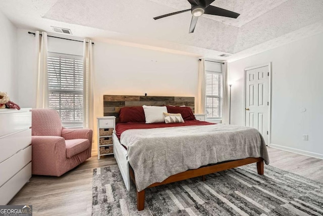 bedroom featuring light wood-type flooring, visible vents, and multiple windows
