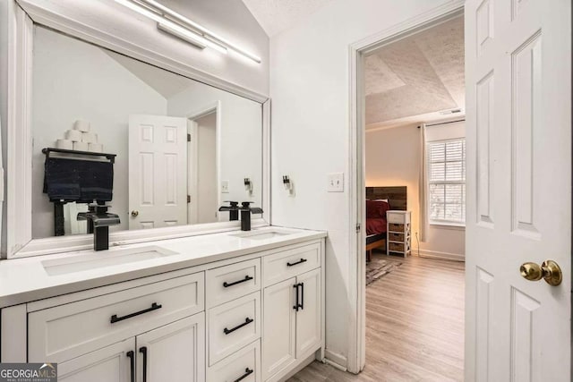 bathroom with a sink, double vanity, wood finished floors, and ensuite bathroom