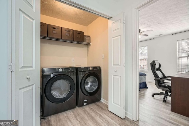 laundry room with a textured ceiling, laundry area, light wood-type flooring, and washing machine and clothes dryer