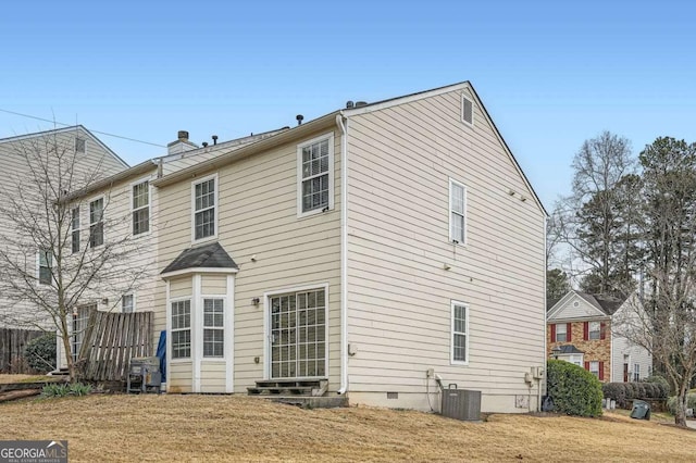 back of property with entry steps, a yard, crawl space, central AC unit, and a chimney