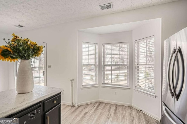 kitchen featuring a textured ceiling, visible vents, freestanding refrigerator, and light wood-type flooring
