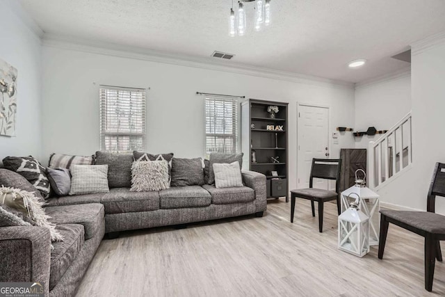 living area featuring plenty of natural light, a textured ceiling, light wood-style flooring, and stairs