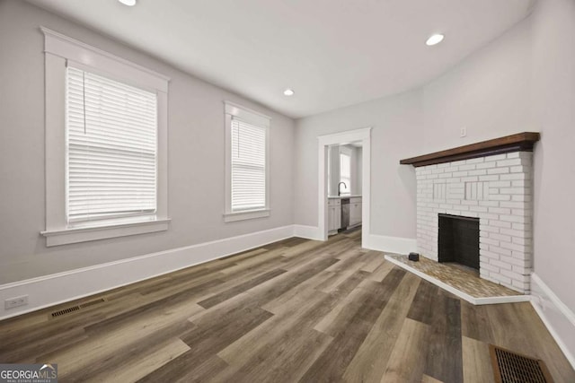 1769 Lyle Ave, Atlanta, GA 30337 - unfurnished living room with wood finished floors, a brick fireplace, and recessed lighting