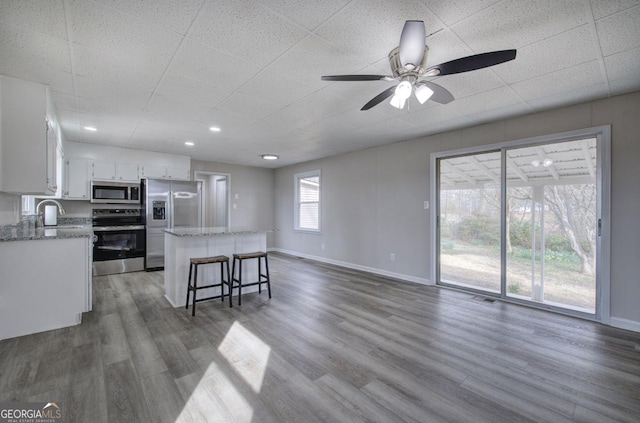 kitchen with a sink, stainless steel appliances, dark wood-type flooring, white cabinetry, and a center island