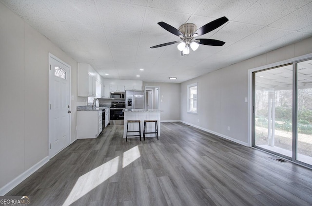 kitchen with a kitchen island, dark wood-type flooring, stainless steel appliances, white cabinetry, and a ceiling fan