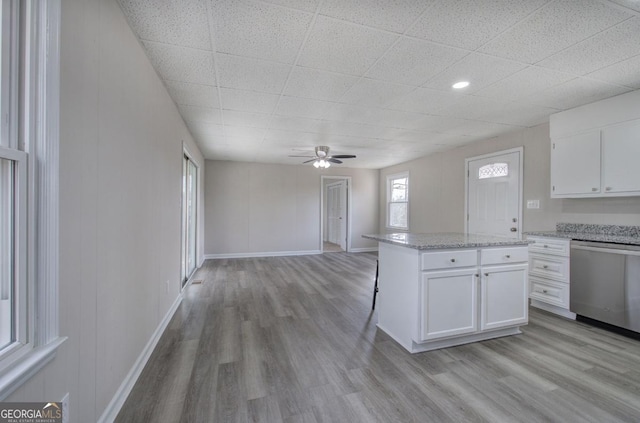 kitchen with light wood-style flooring, a ceiling fan, white cabinetry, baseboards, and dishwasher