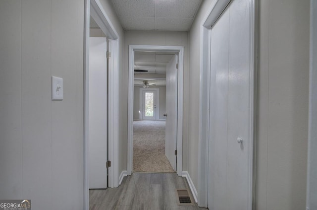 corridor with visible vents, a paneled ceiling, and light wood-style flooring