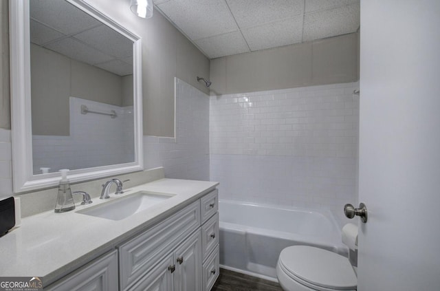 bathroom with vanity, a drop ceiling, toilet, and shower / bathtub combination