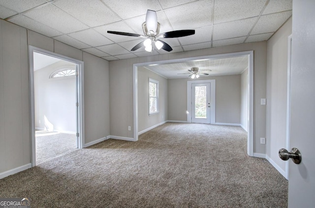 carpeted spare room featuring baseboards, a paneled ceiling, and a ceiling fan