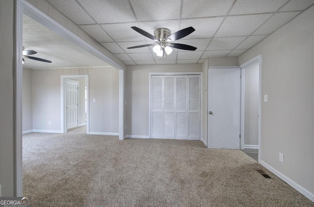 unfurnished bedroom featuring a closet, carpet, visible vents, and a drop ceiling