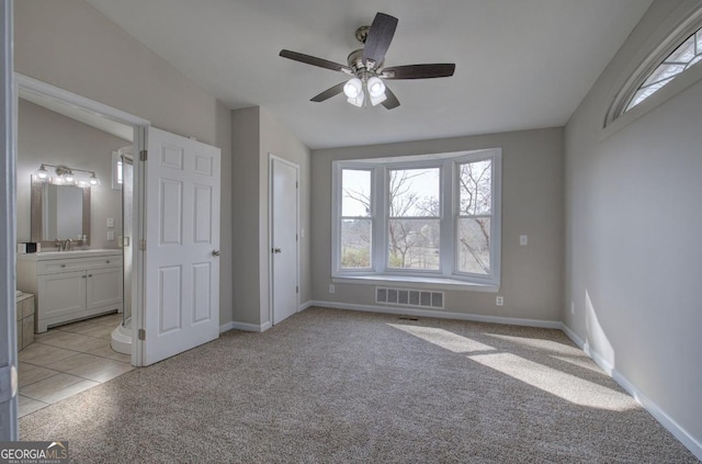 unfurnished bedroom with connected bathroom, baseboards, visible vents, and light carpet