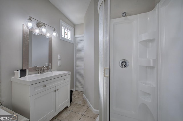 bathroom with baseboards, vanity, tile patterned flooring, and a walk in shower