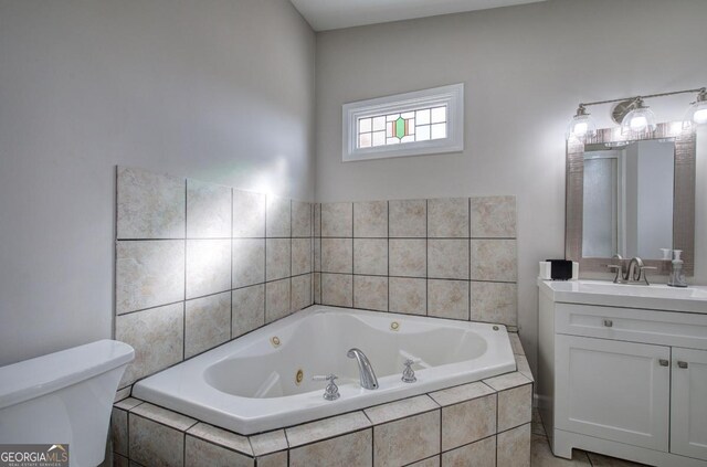 full bathroom featuring toilet, a jetted tub, and vanity