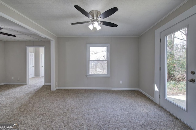 carpeted spare room with ornamental molding, a wealth of natural light, and ceiling fan