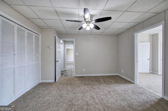 unfurnished bedroom featuring a closet, a drop ceiling, baseboards, and carpet floors