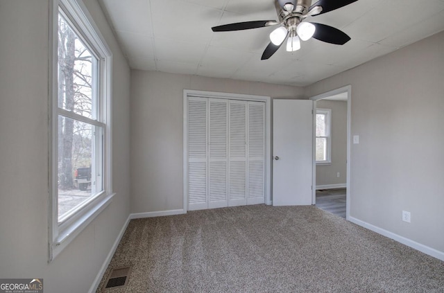 unfurnished bedroom featuring visible vents, a ceiling fan, a closet, carpet, and baseboards