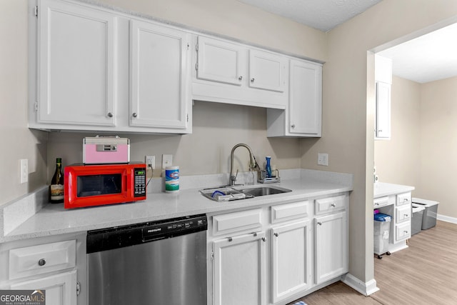 kitchen with stainless steel dishwasher, light countertops, white cabinets, and a sink