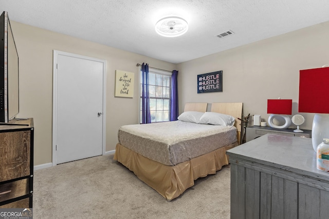 bedroom with baseboards, light colored carpet, visible vents, and a textured ceiling