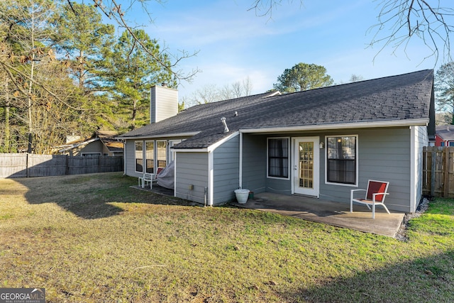 back of house featuring roof with shingles, a yard, a fenced backyard, a chimney, and a patio area