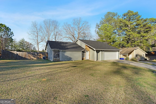 exterior space with a yard, a garage, concrete driveway, and fence