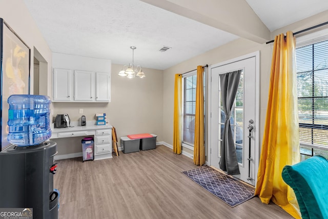 office featuring visible vents, baseboards, a chandelier, light wood-style flooring, and a textured ceiling