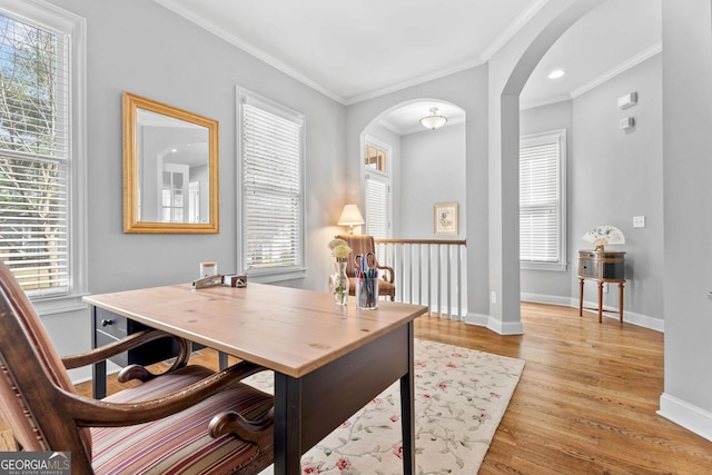 office area featuring ornamental molding, light wood-style floors, arched walkways, and baseboards