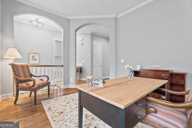 office area with crown molding, wood finished floors, arched walkways, and baseboards