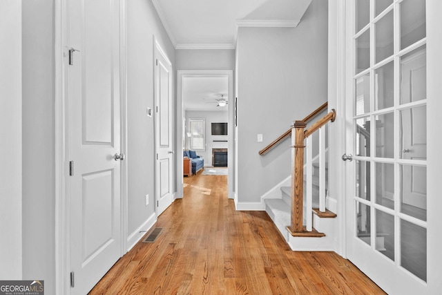 foyer entrance with visible vents, crown molding, ceiling fan, stairway, and wood finished floors