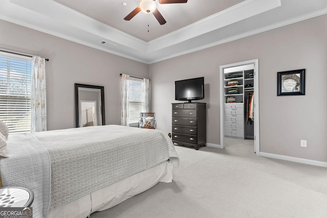 bedroom featuring visible vents, a walk in closet, a tray ceiling, carpet flooring, and baseboards