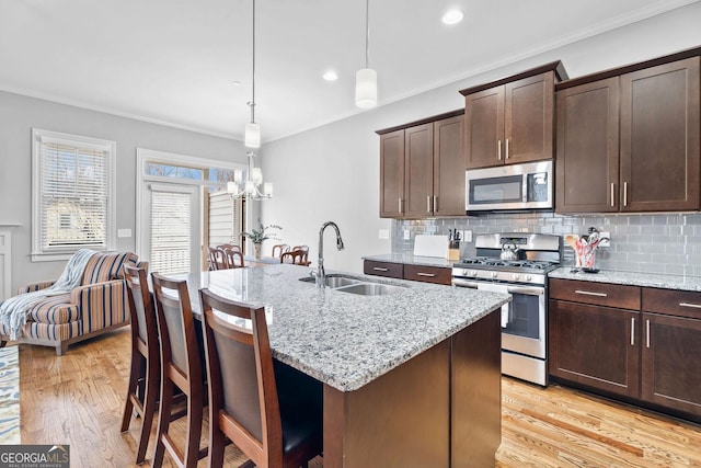 kitchen featuring crown molding, light wood-type flooring, appliances with stainless steel finishes, and a sink