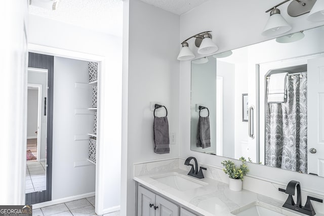 bathroom featuring a sink, a textured ceiling, double vanity, and tile patterned flooring