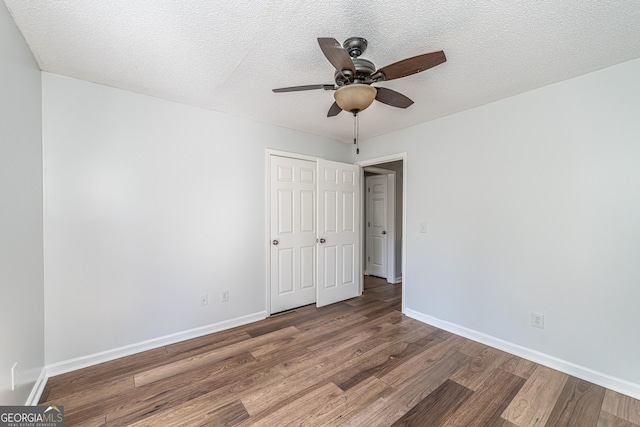 unfurnished bedroom with a textured ceiling, baseboards, and wood finished floors