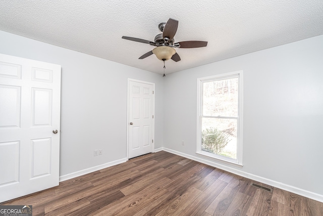 unfurnished bedroom featuring visible vents, dark wood-type flooring, ceiling fan, baseboards, and a textured ceiling