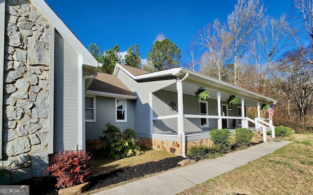 view of side of home with stone siding and a porch