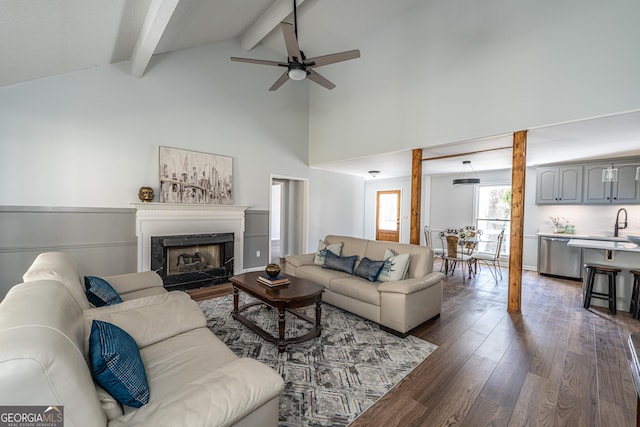 living area featuring beamed ceiling, high vaulted ceiling, a ceiling fan, wood finished floors, and a fireplace