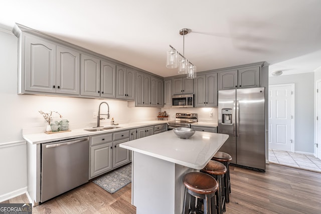 kitchen with a sink, light wood-type flooring, appliances with stainless steel finishes, and gray cabinets