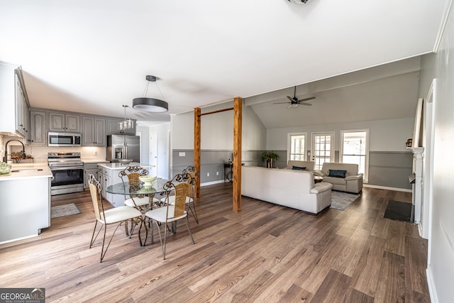 dining space featuring light wood-type flooring, baseboards, a ceiling fan, and vaulted ceiling