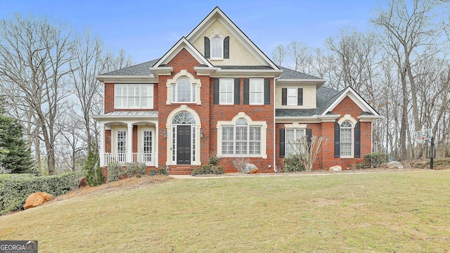 view of front of house with a front yard, brick siding, and roof with shingles